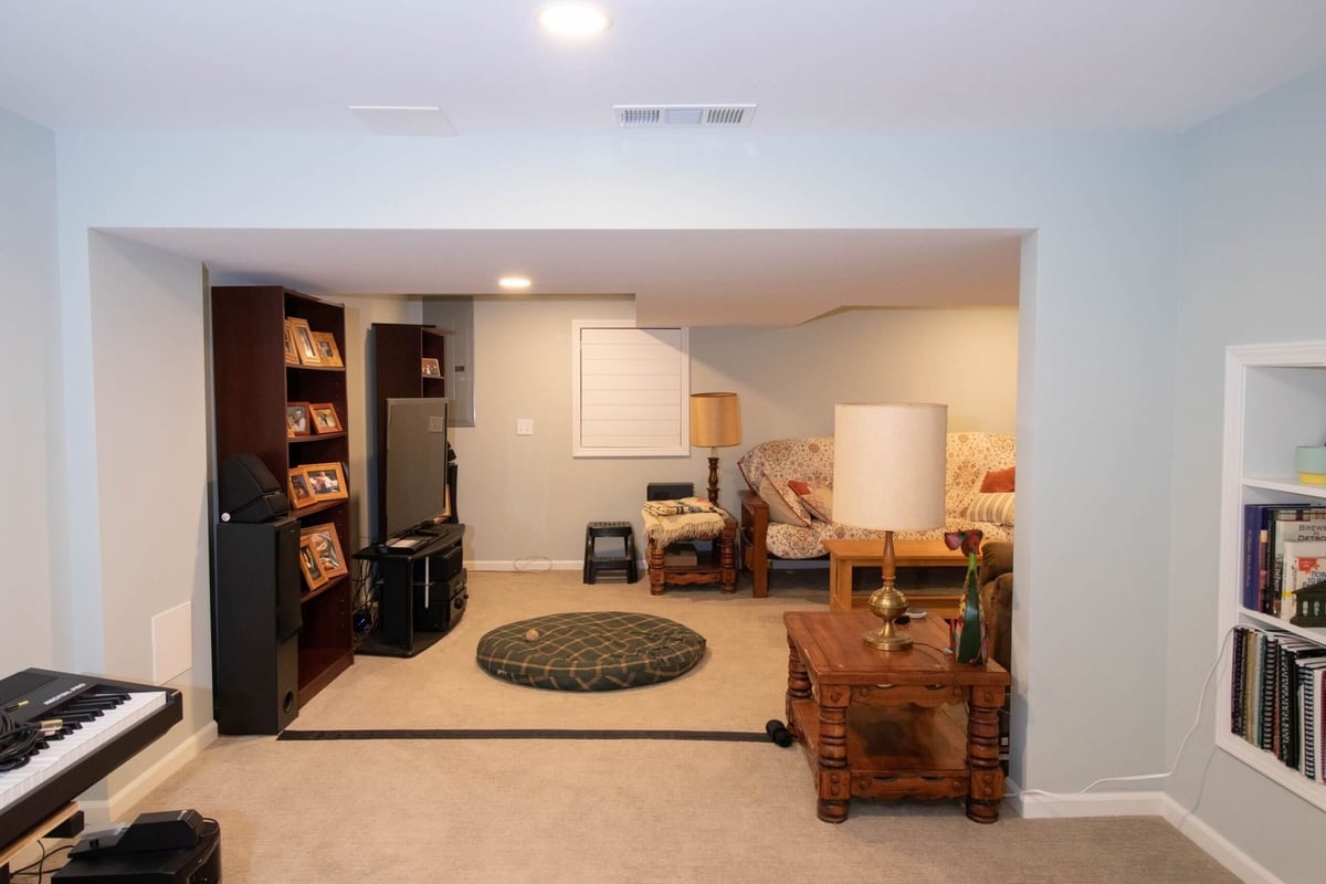 Finished basement living area with carpet flooring and seating space by Odd Fellows Contracting in Lansing, MI.