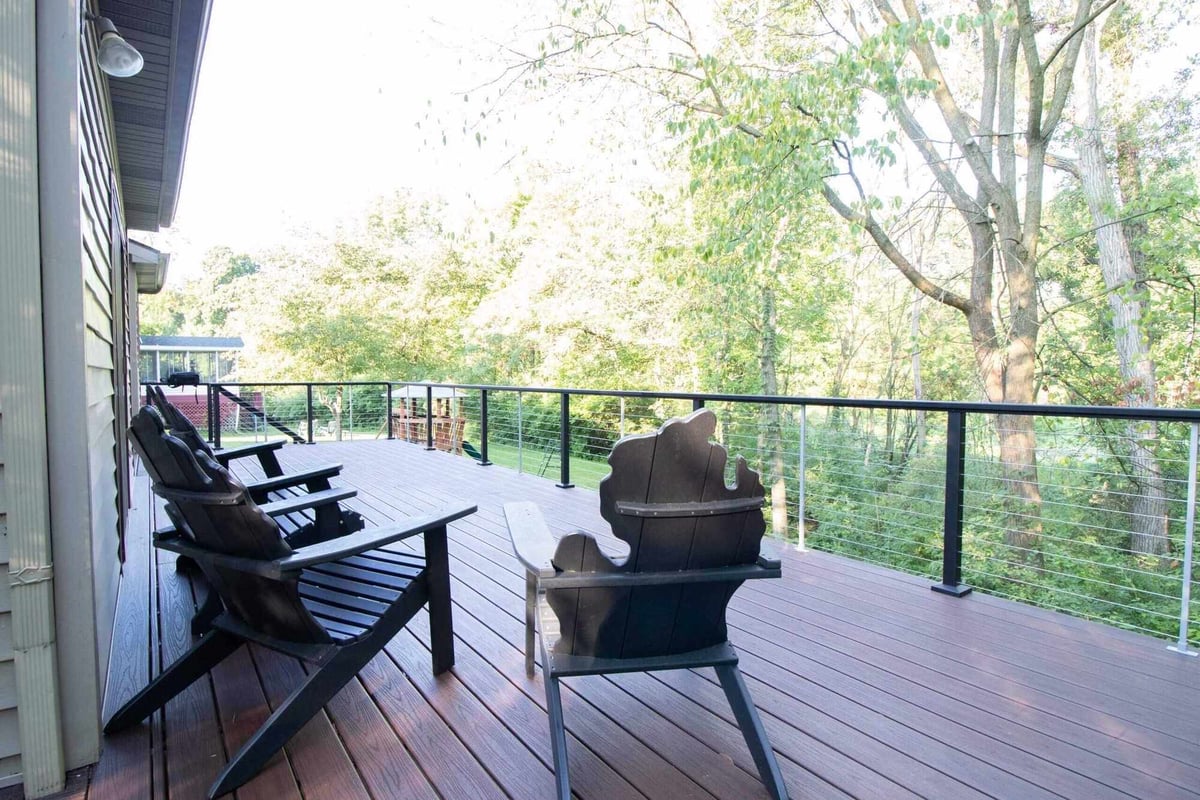 large composite deck with cable railing overlooking wooded landscape in Haslett, MI