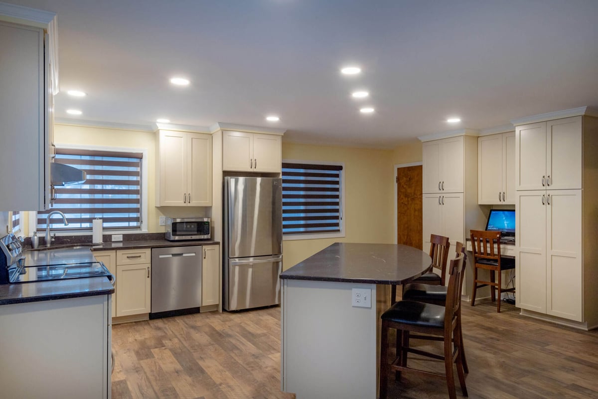 open concept kitchen remodel with large quartz island, stainless appliances, and white shaker cabinets by Odd Fellows Contracting in Lansing, MI