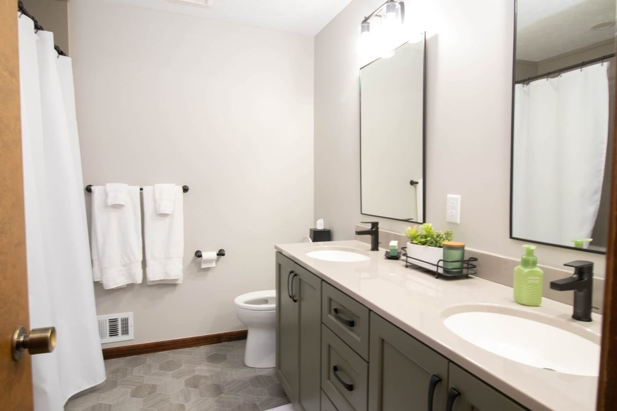 remodeled bathroom featuring double sink vanity and hex tile flooring by Odd Fellows Contracting in Okemos, MI