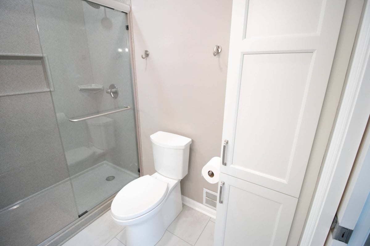 remodeled bathroom shower with sliding glass enclosure and updated fixtures by Odd Fellows Contracting in Williamston, MI