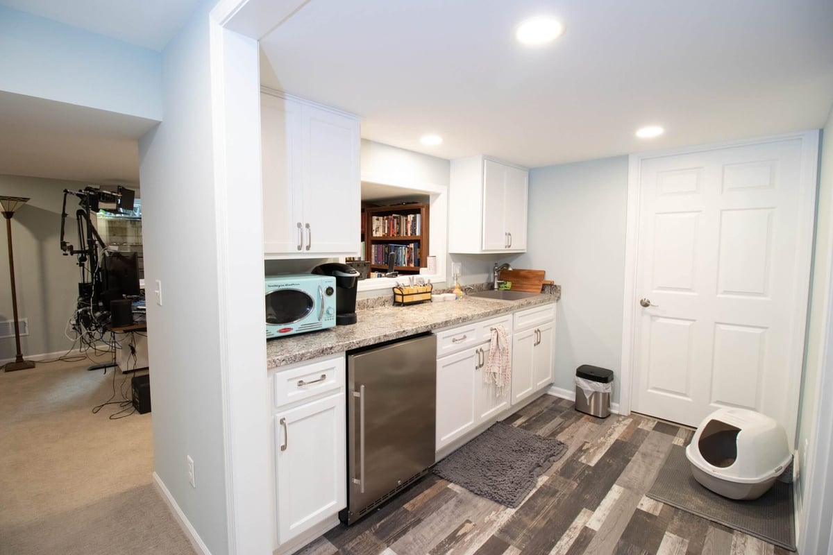 Basement kitchenette remodel with white cabinets, countertop, and mini fridge by Odd Fellows Contracting in Lansing, MI.