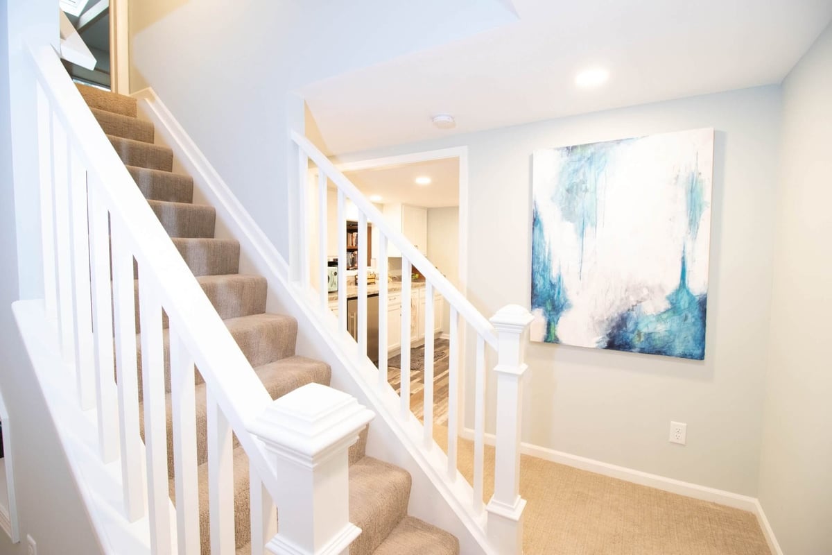Basement staircase with carpeted steps and updated railing during remodel by Odd Fellows Contracting in Lansing, MI.