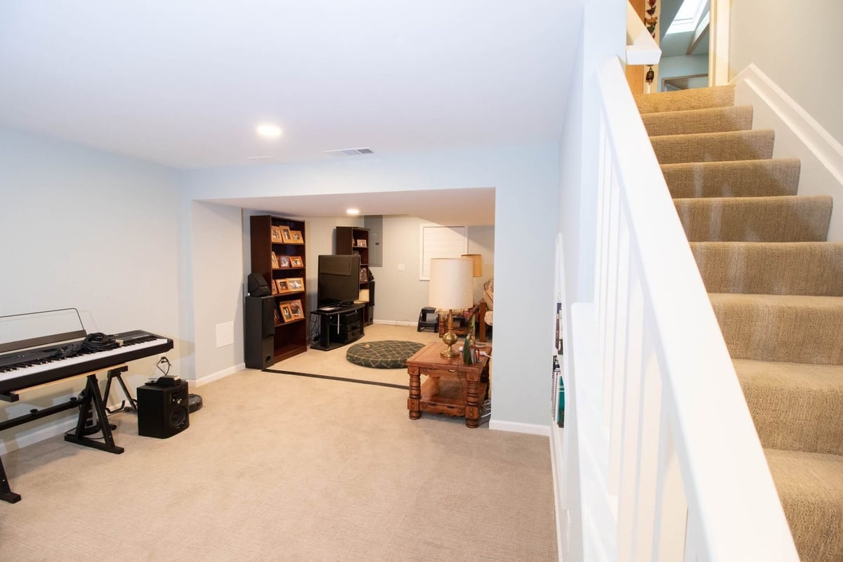 Lansing basement remodel featuring staircase with carpet and white railing by Odd Fellows Contracting.
