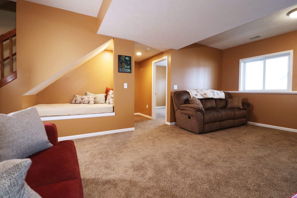 finished basement living room with carpet and built in seating by Odd Fellows Contracting in Williamston MI