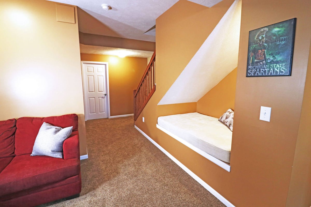 finished basement seating area with custom built in bench under stairs by Odd Fellows Contracting in Williamston MI