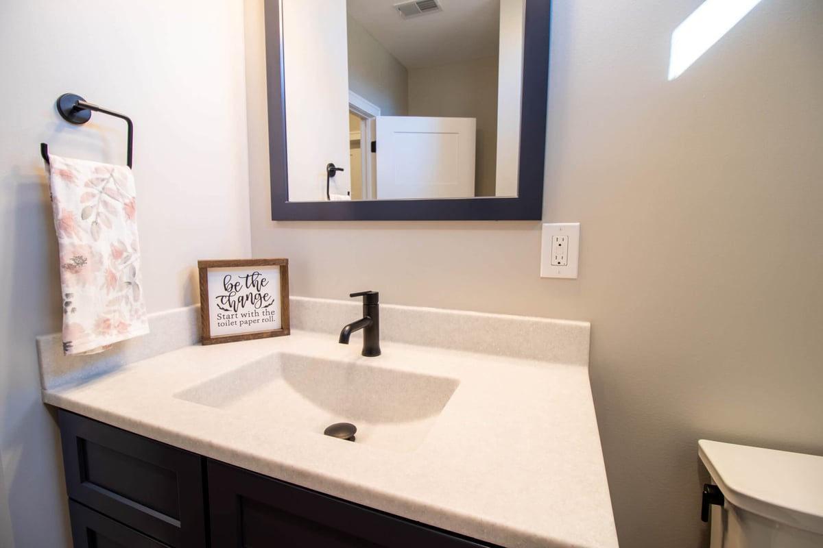 bathroom vanity close up by Odd Fellows Contracting in Mason MI with solid surface countertop and matte black faucet