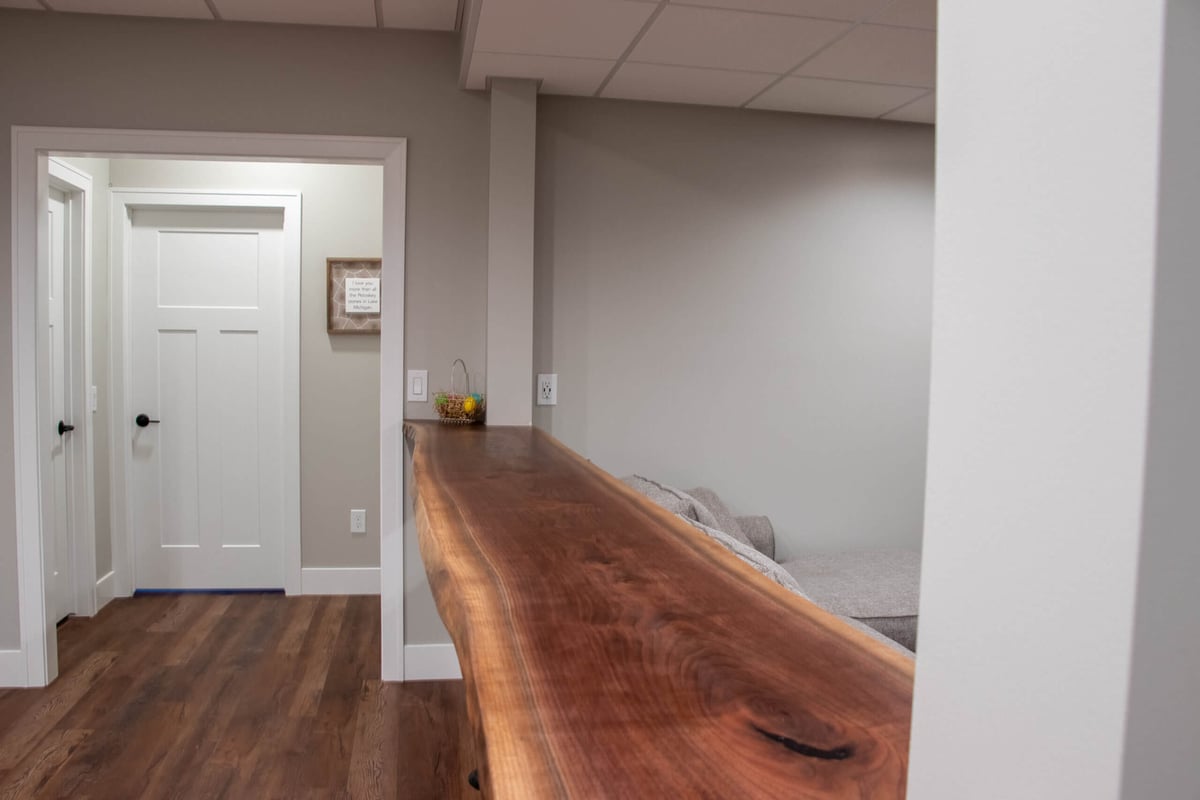 finished basement bar area by Odd Fellows Contracting in Mason MI with wood countertop and modern layout