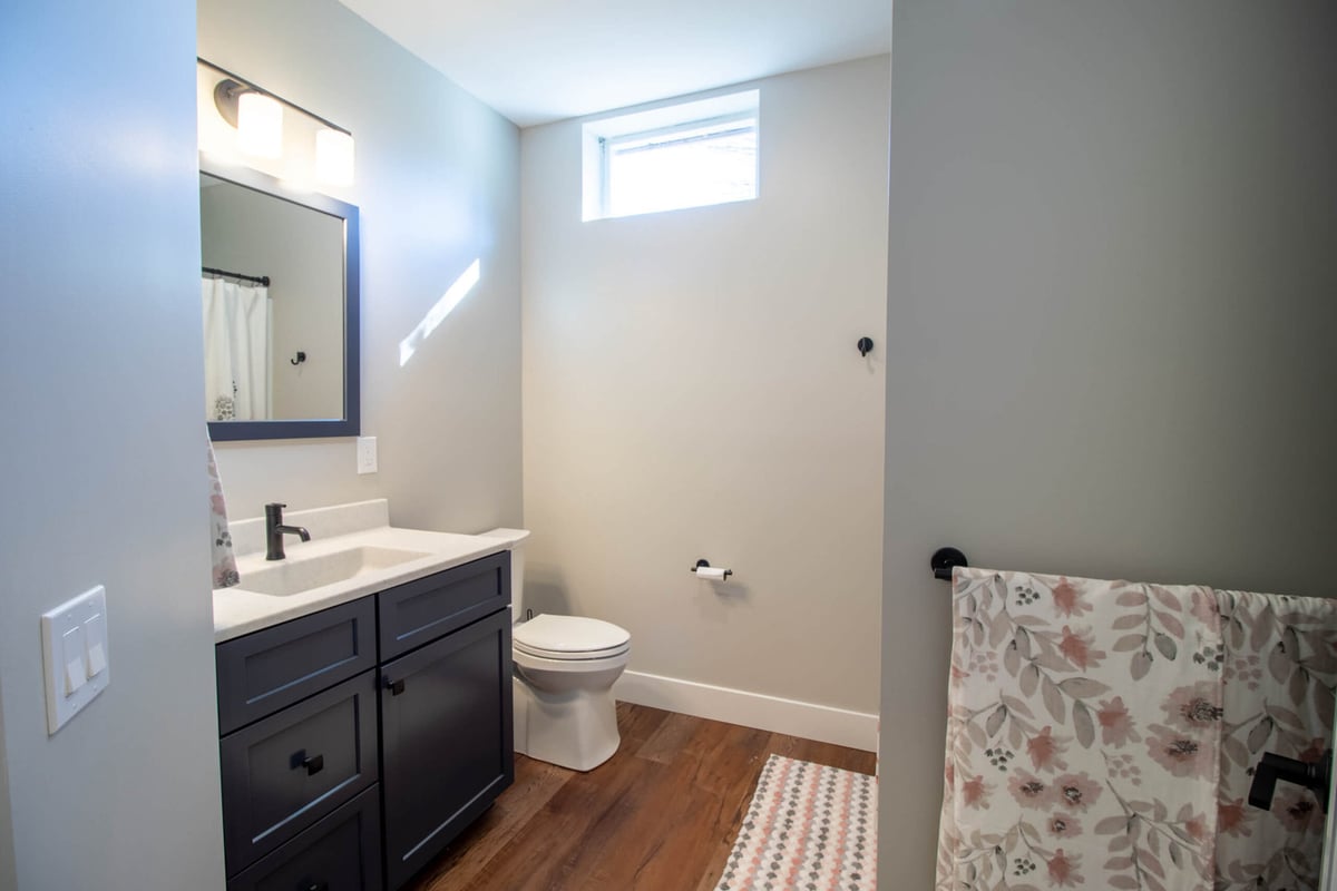 finished basement bathroom by Odd Fellows Contracting in Mason MI with modern vanity and wood flooring