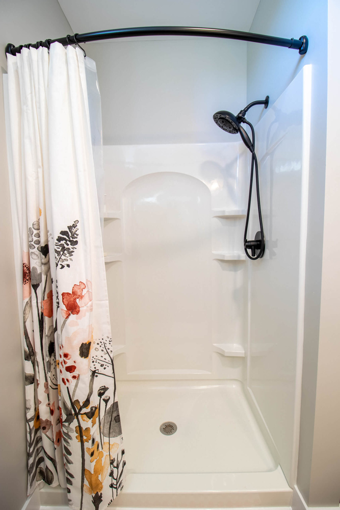 finished basement shower by Odd Fellows Contracting in Mason MI featuring modern hardware and curtain