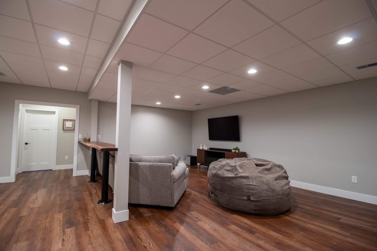 modern basement living room by Odd Fellows Contracting in Mason MI with entertainment space and neutral tones