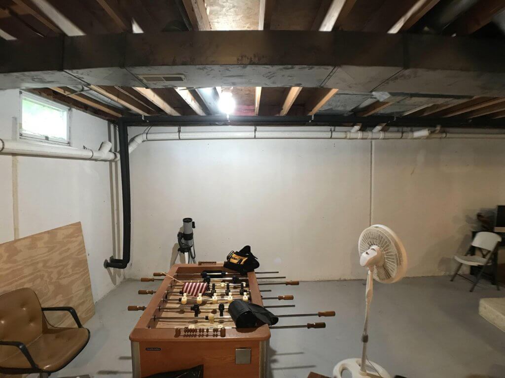 unfinished basement before remodel by Odd Fellows Contracting in Mason MI with exposed beams and concrete floor