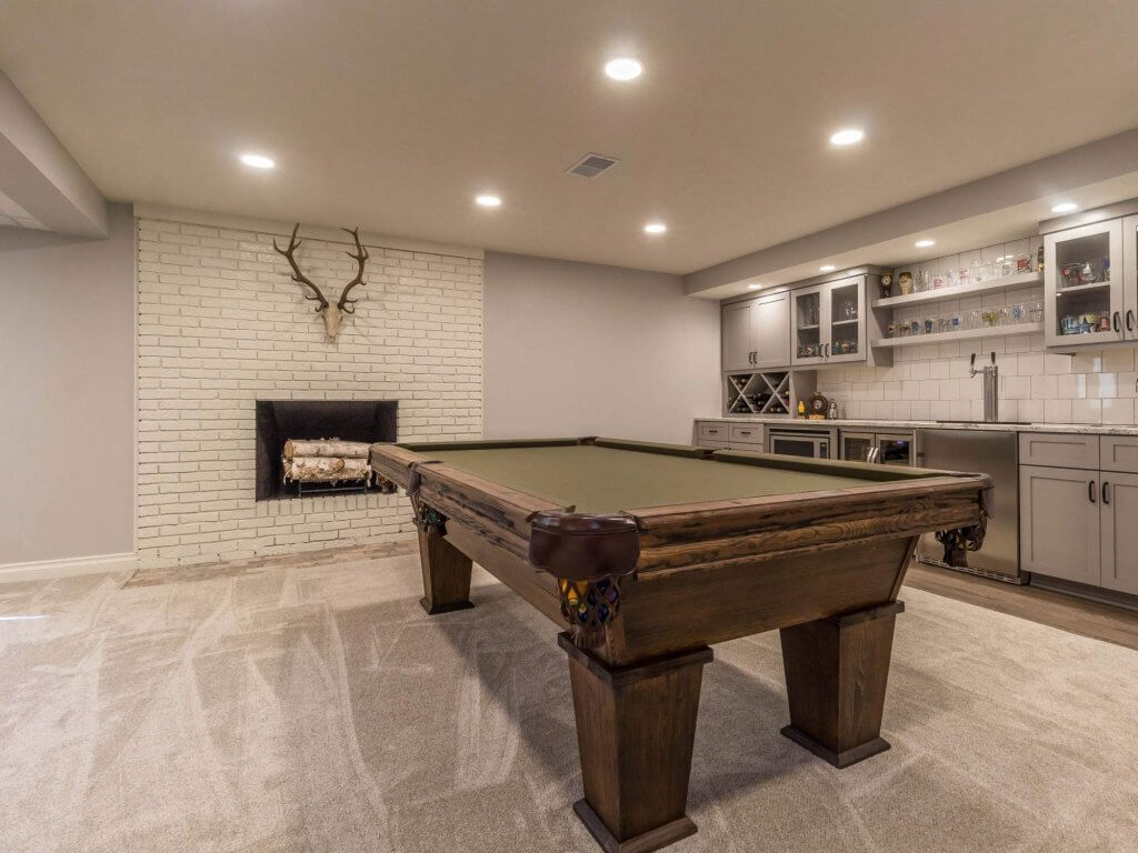 finished basement game room with pool table and brick fireplace by Odd Fellows Contracting in East Lansing MI