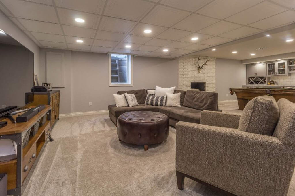 finished basement living area with sectional couch and recessed lighting by Odd Fellows Contracting in East Lansing MI