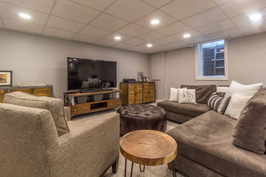 remodeled basement lounge area with TV and seating by Odd Fellows Contracting in East Lansing MI