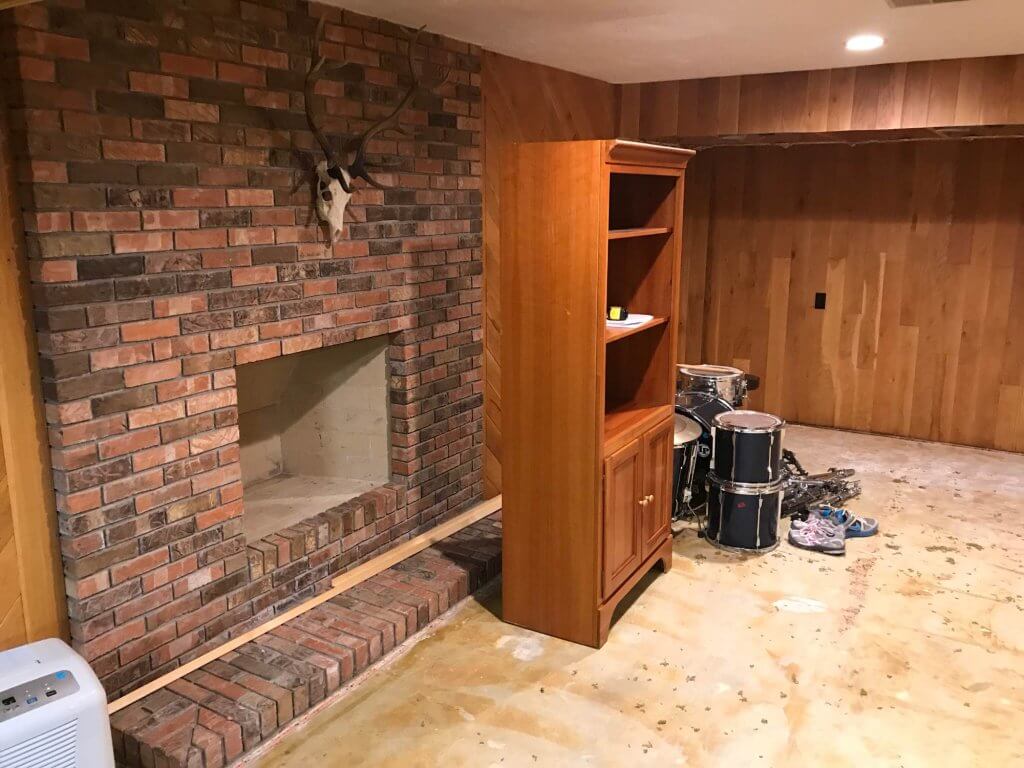 unfinished basement with brick fireplace before remodel by Odd Fellows Contracting in East Lansing MI