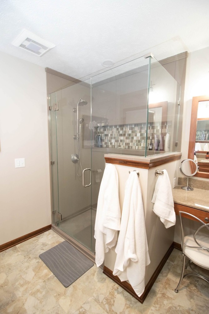 spacious bathroom remodel featuring wood vanity and glass shower by Odd Fellows Contracting in Okemos, MI