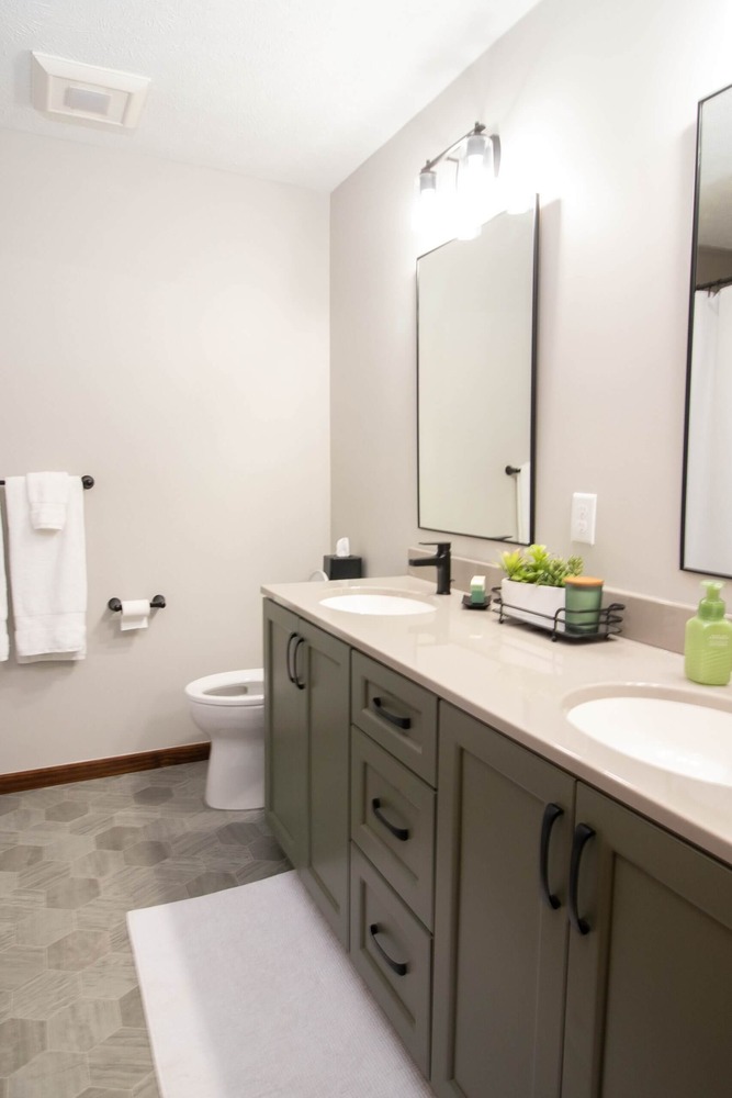 modern double vanity with green cabinetry installed during bathroom remodel by Odd Fellows Contracting in Okemos, MI