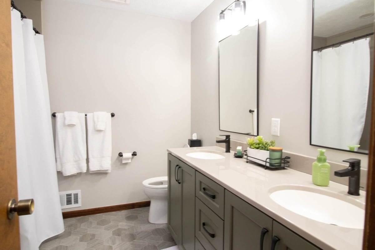 remodeled bathroom featuring double sink vanity and hex tile flooring by Odd Fellows Contracting in Okemos, MI