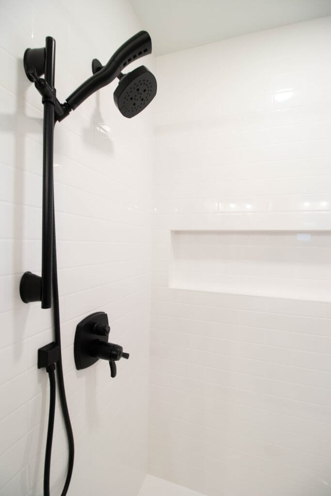 close-up of matte black shower fixture and tile wall in bathroom remodel by Odd Fellows Contracting in Okemos, MI