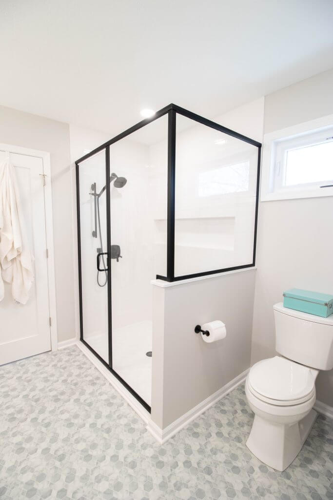 modern shower with white tile walls and black hardware from bathroom remodel by Odd Fellows Contracting in Okemos, MI