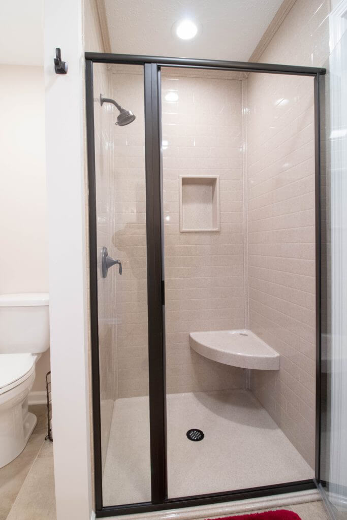 modern walk-in shower with niche and dark fixtures by Odd Fellows Contracting in Lansing, MI