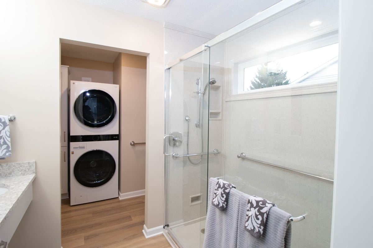 updated bathroom with stacked washer dryer and walk-in shower by Odd Fellows Contracting in Dewitt, MI