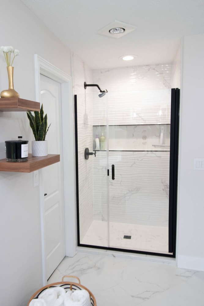 Bathroom remodel walk-in shower with marble tile and black framed glass door by Odd Fellows Contracting in DeWitt, MI.