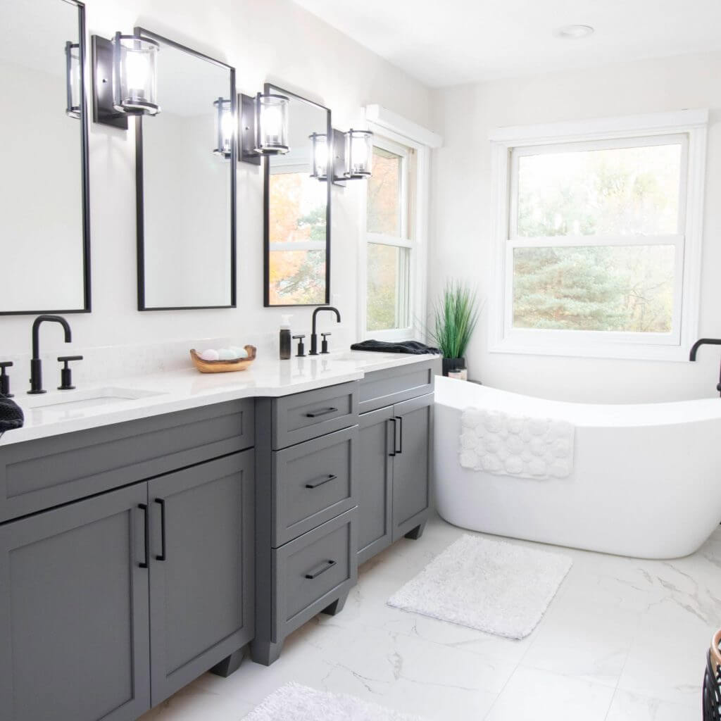 Completed bathroom remodel with gray double vanity and freestanding tub by Odd Fellows Contracting in DeWitt, MI.