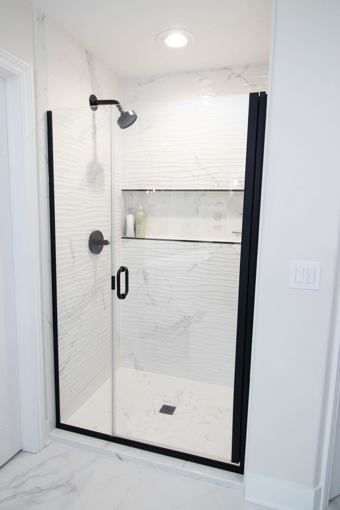 Updated bathroom shower with modern tile and black fixtures by Odd Fellows Contracting in DeWitt, MI.