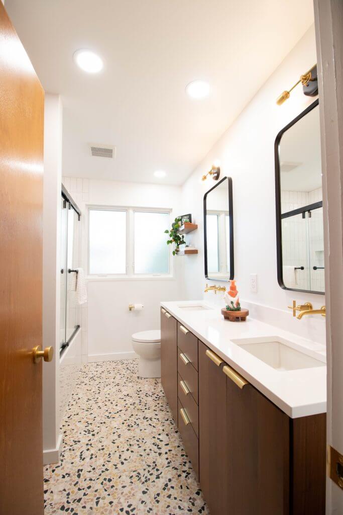 modern bathroom remodel with wood vanity, gold fixtures, and large mirrors by Odd Fellows Contracting in Lansing, MI
