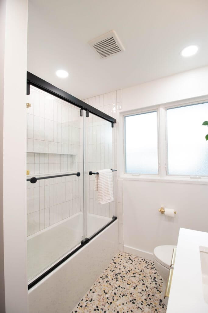tiled bathtub shower with gold fixtures from bathroom remodel by Odd Fellows Contracting in Lansing, MI