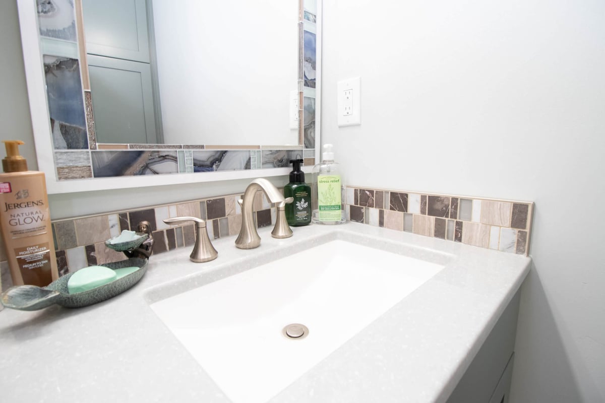 bathroom vanity close-up with integrated sink and tile backsplash from remodel by Odd Fellows Contracting in Laingsburg, MI