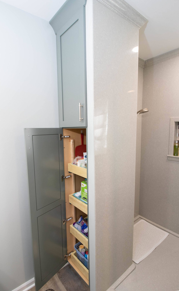 custom bathroom storage cabinet with pull-out shelves installed during bathroom remodel by Odd Fellows Contracting in Laingsburg, MI