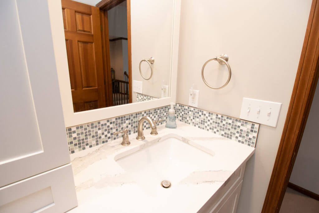 Close-up of quartz vanity countertop and tile backsplash by Odd Fellows Contracting in Okemos, MI