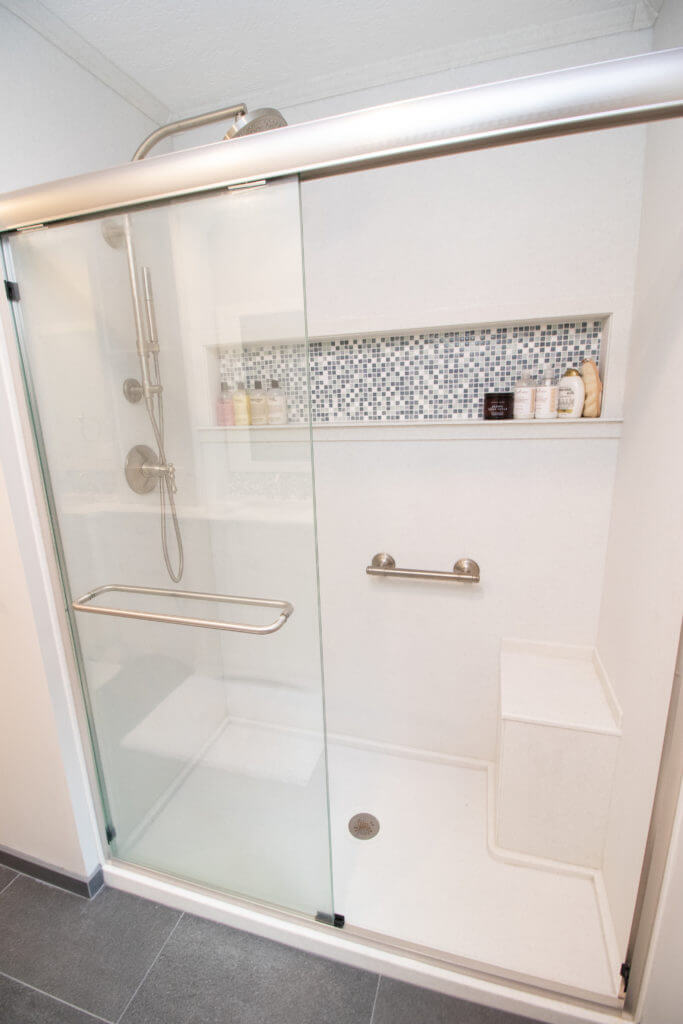Walk-in shower with glass door and bench from bathroom remodel by Odd Fellows Contracting in Okemos, MI