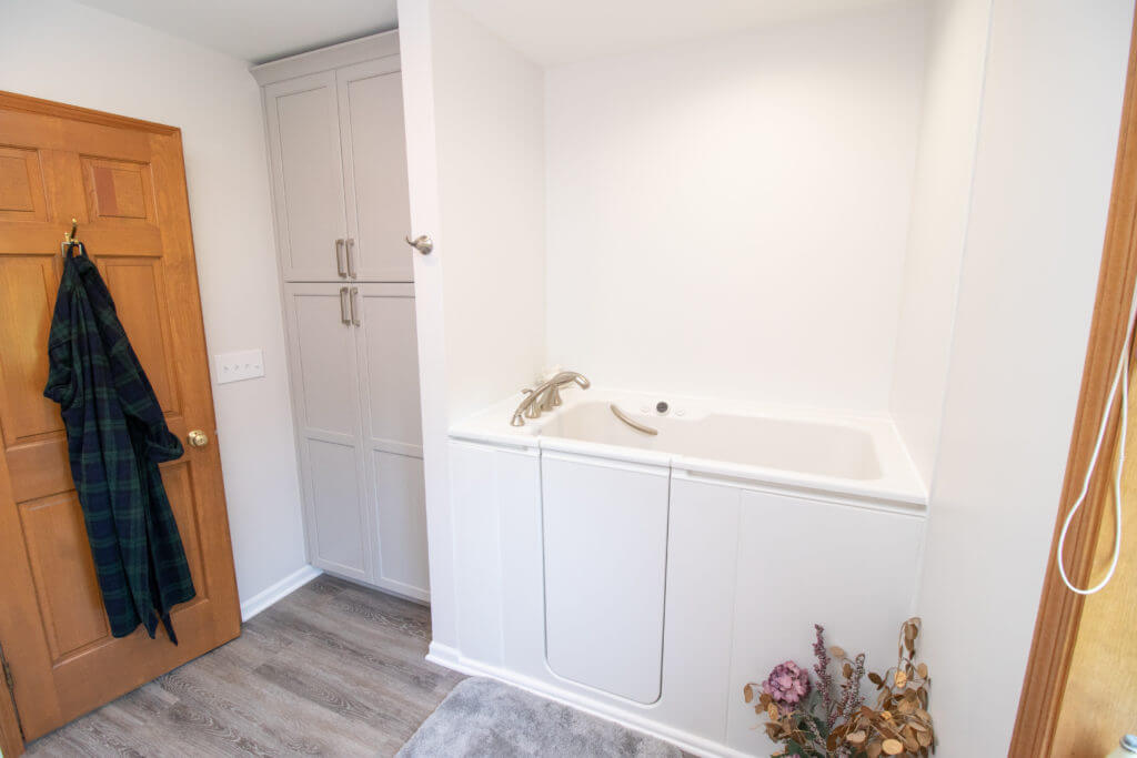 Modern bathroom renovation with tub surround and cabinet storage by Odd Fellows Contracting in Williamston, MI