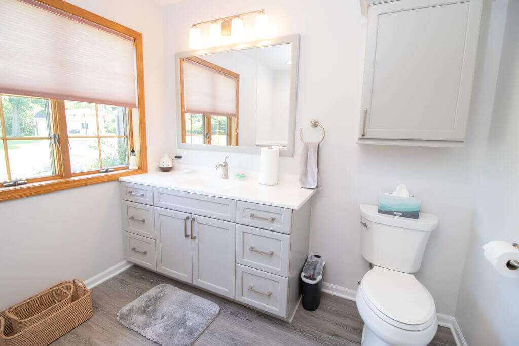 Updated bathroom with modern vanity cabinetry and lighting by Odd Fellows Contracting in Williamston, MI