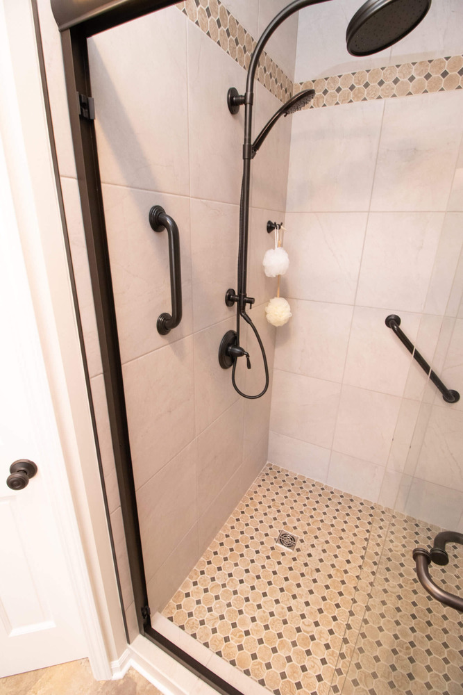 bathroom remodel shower detail with tile walls, glass enclosure, and mosaic tile floor by Odd Fellows Contracting in Webberville, MI