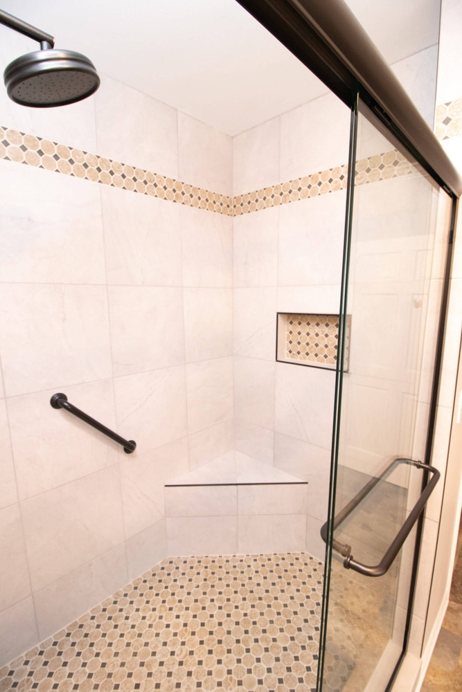 close up of tiled walk in shower with mosaic floor and built in niche by Odd Fellows Contracting in Webberville, MI