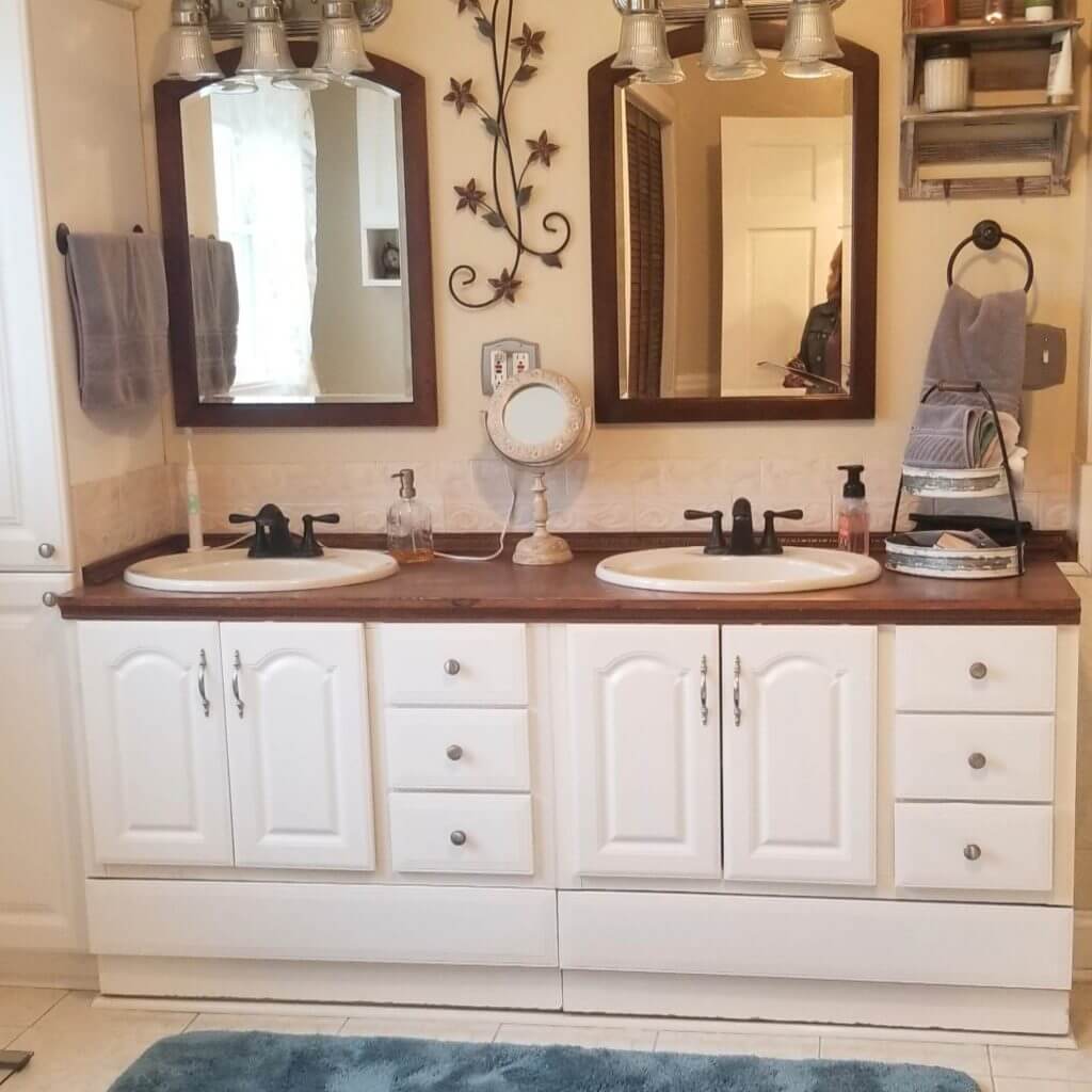 pre remodel bathroom with double vanity cabinet and framed mirrors before renovation by Odd Fellows Contracting in Webberville, MI