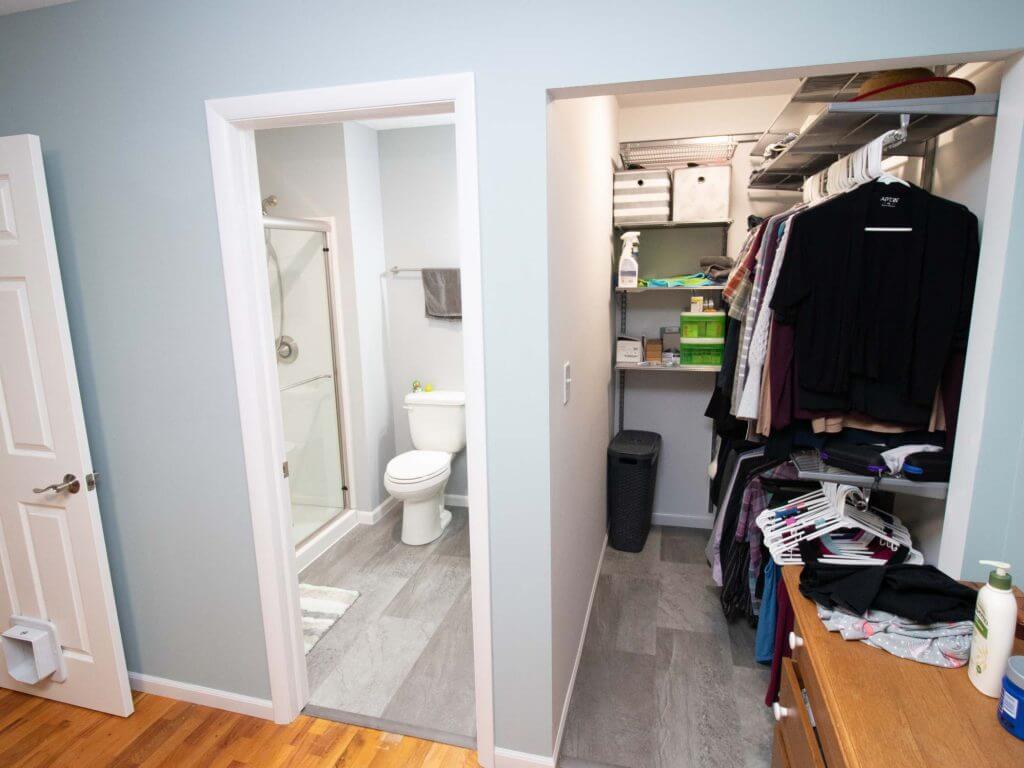 New bathroom and walk-in closet addition completed by Odd Fellows Contracting in Haslett, MI featuring shower, toilet, and organized closet storage)