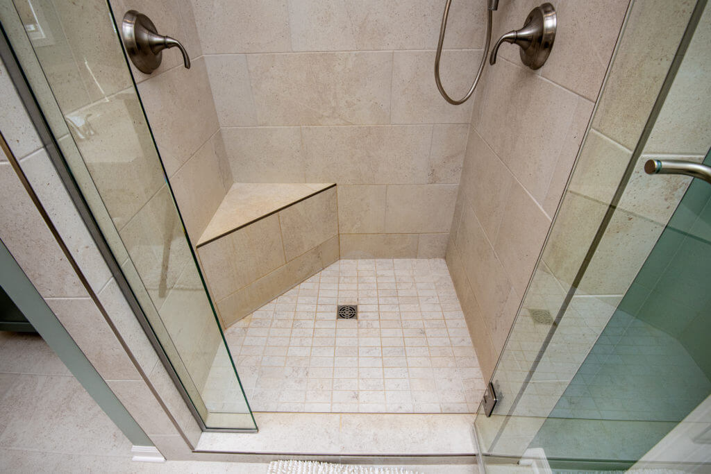 tiled walk in shower with bench seat in bathroom remodel by Odd Fellows Contracting Mason MI