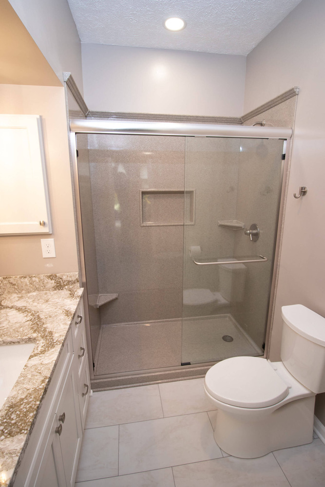 modern bathroom remodel with tile flooring, walk-in shower, and stone vanity top by Odd Fellows Contracting in Williamston, MI