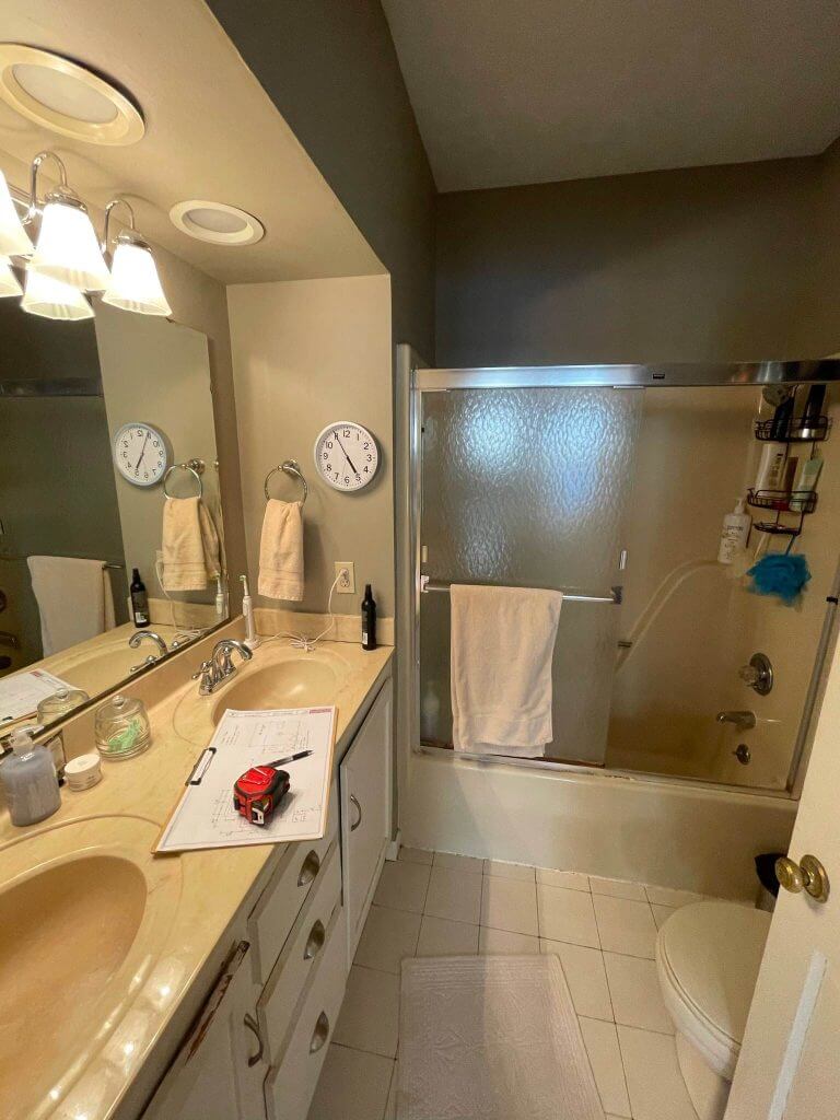 outdated bathroom before remodel with double sink vanity and tub shower combination by Odd Fellows Contracting in Williamston, MI