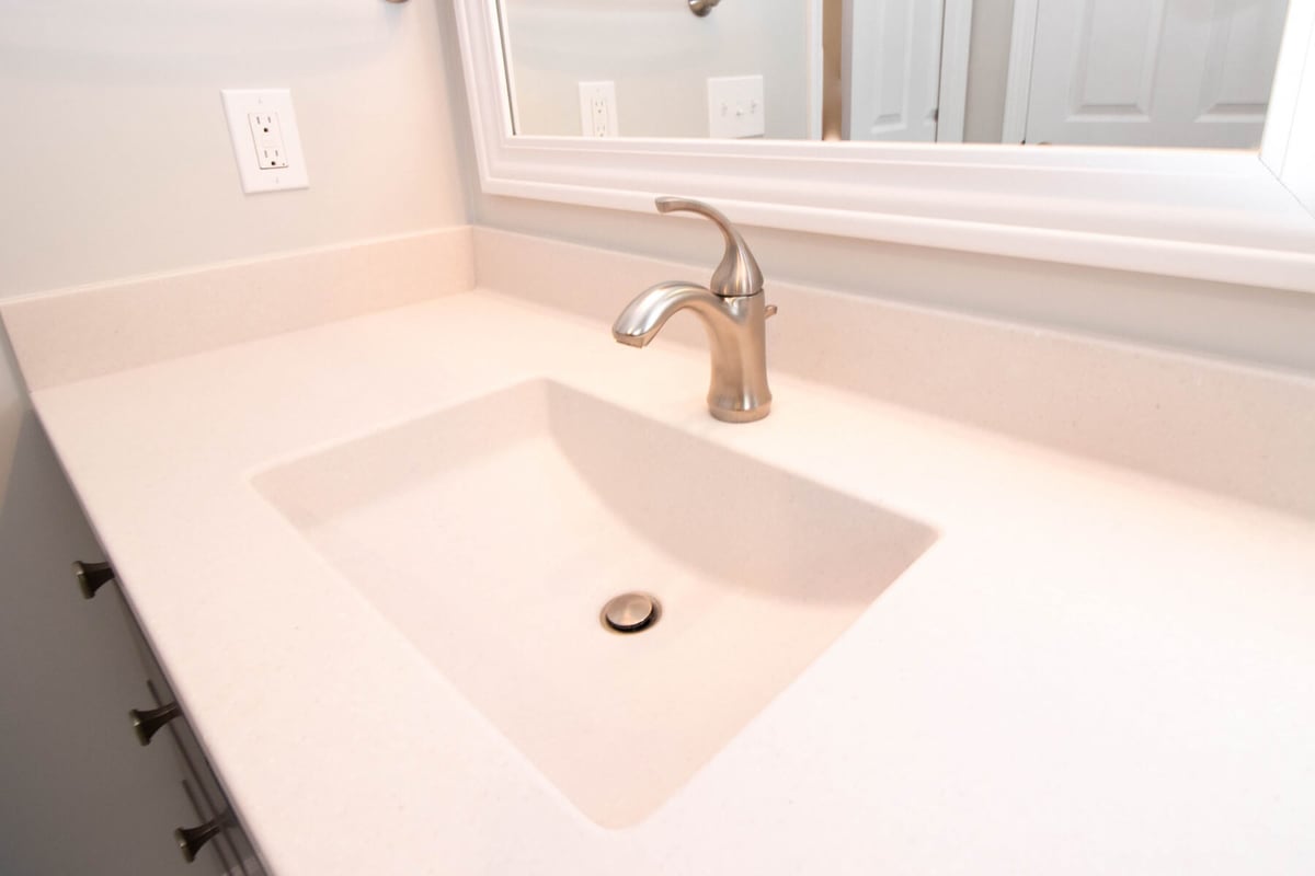 Mason MI bathroom renovation by Odd Fellows Contracting featuring modern faucet and solid surface vanity top