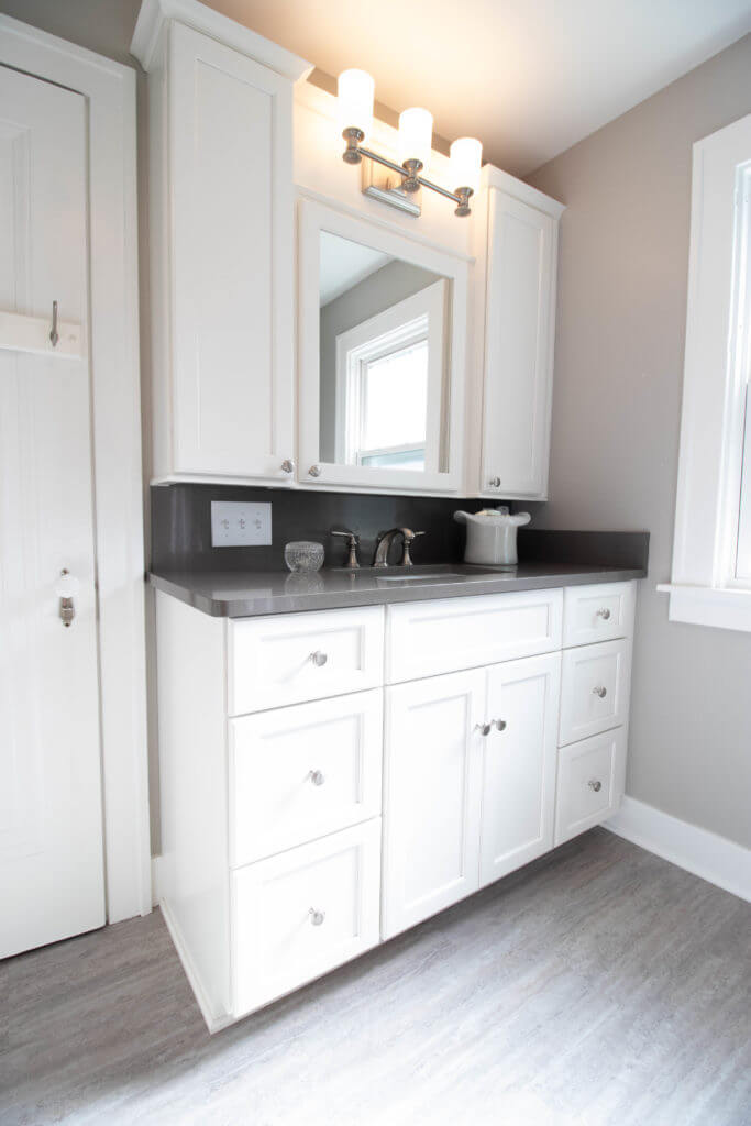 bathroom vanity and storage by Odd Fellows Contracting in East Lansing MI with white cabinets and hooks