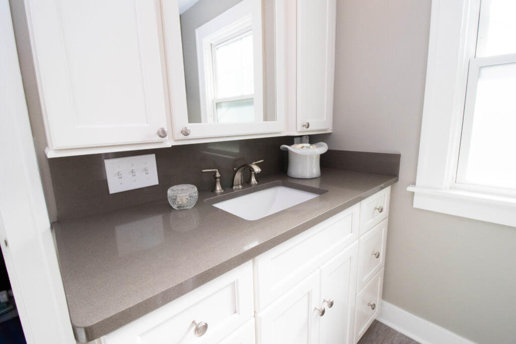 updated bathroom vanity by Odd Fellows Contracting in East Lansing MI with white cabinetry and solid surface countertop