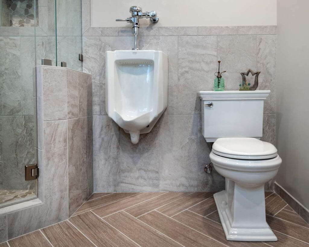 bathroom remodel with tile flooring toilet and urinal installation by Odd Fellows Contracting in Okemos, MI