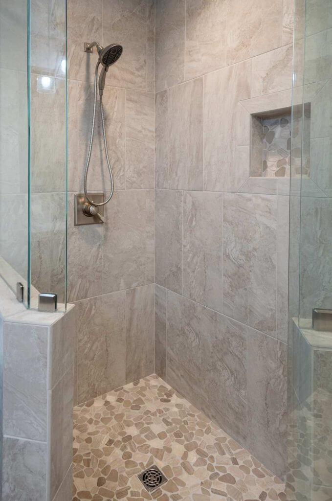 custom bathroom shower with pebble tile floor and wall niche by Odd Fellows Contracting in Okemos MI